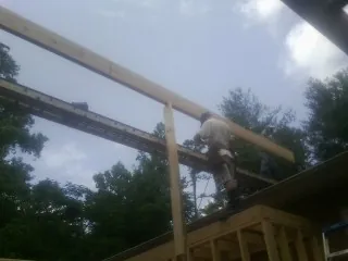Carpenter setting a ridge beam over a new addition frame — Ice Dam Removal by Roofing Brothers in Clifton Park