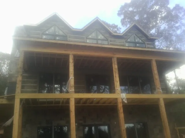 Dormers and porch framing on a large log home under construction — Roof Coating work by our crew in Clifton Park