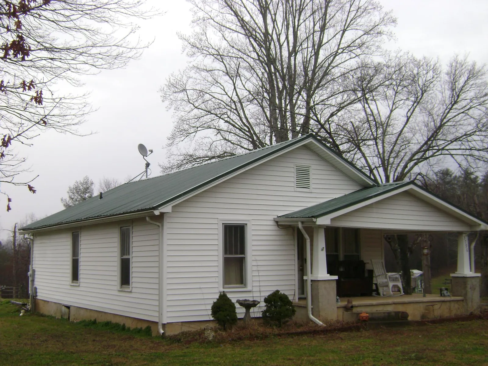 Green metal roof on a white bungalow with a side porch in Clifton Park