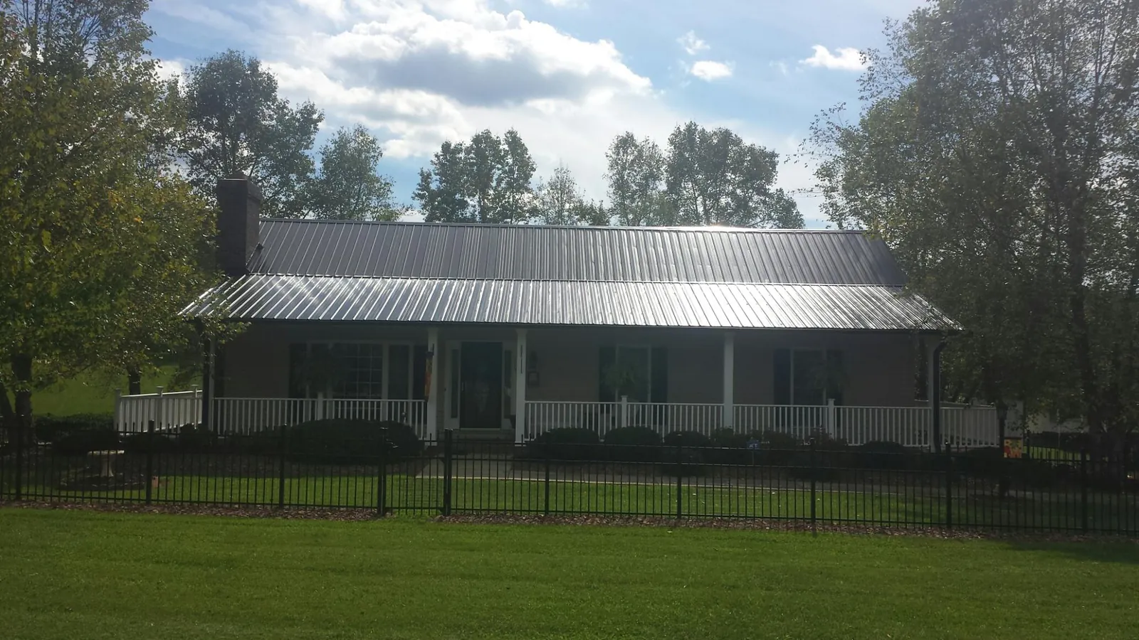 Gray metal roof on a brick ranch with a full width front porch — Gutter Guard Installation work by our crew in Clifton Park