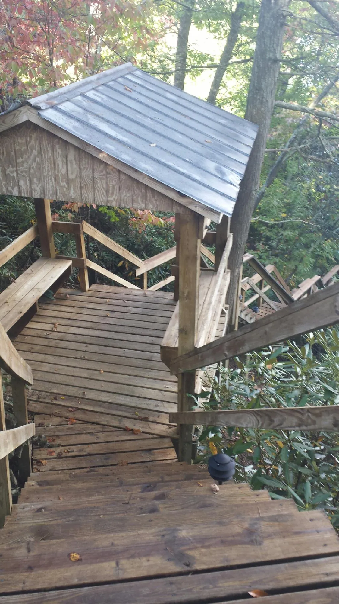Metal roofed shelter over wooden steps on a wooded walkway — Skylight Repair & Installation work by our crew in Clifton Park