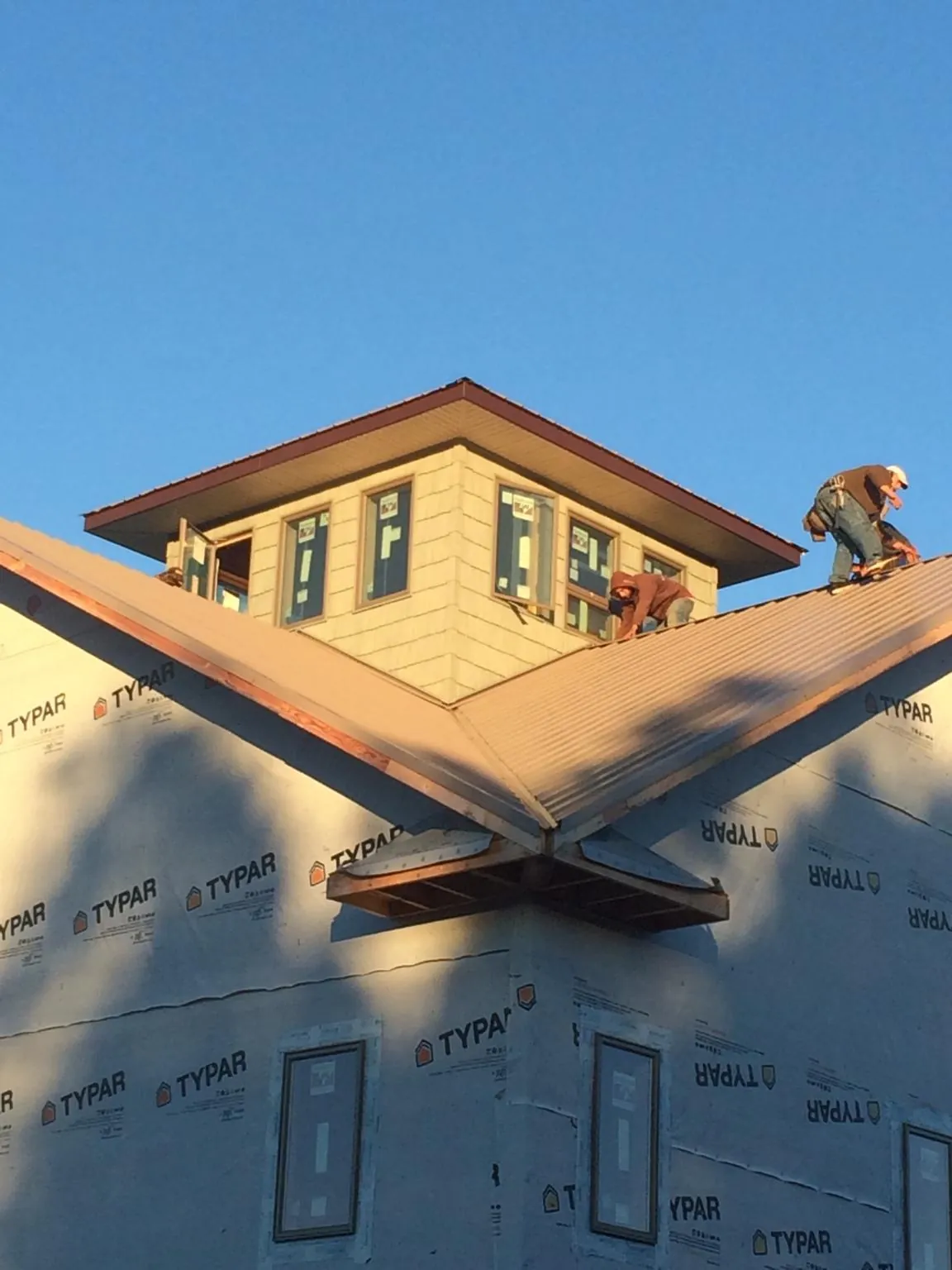 Roofers working around a rooftop cupola on a new metal roof at sunset — Roof Waterproofing in Clifton Park by Roofing Brothers